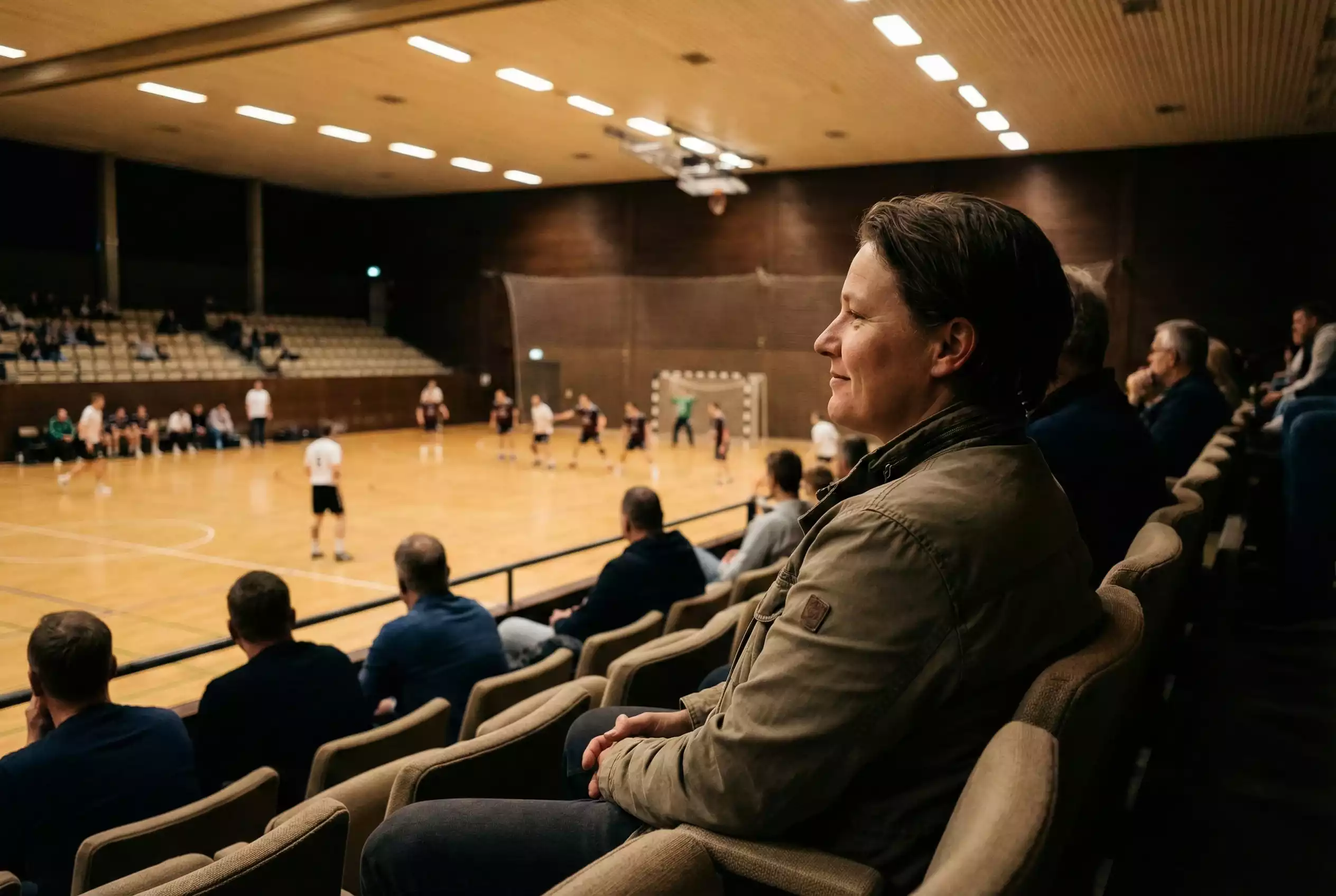 Personne regardant sereinement un match de handball depuis les tribunes sans téléphone