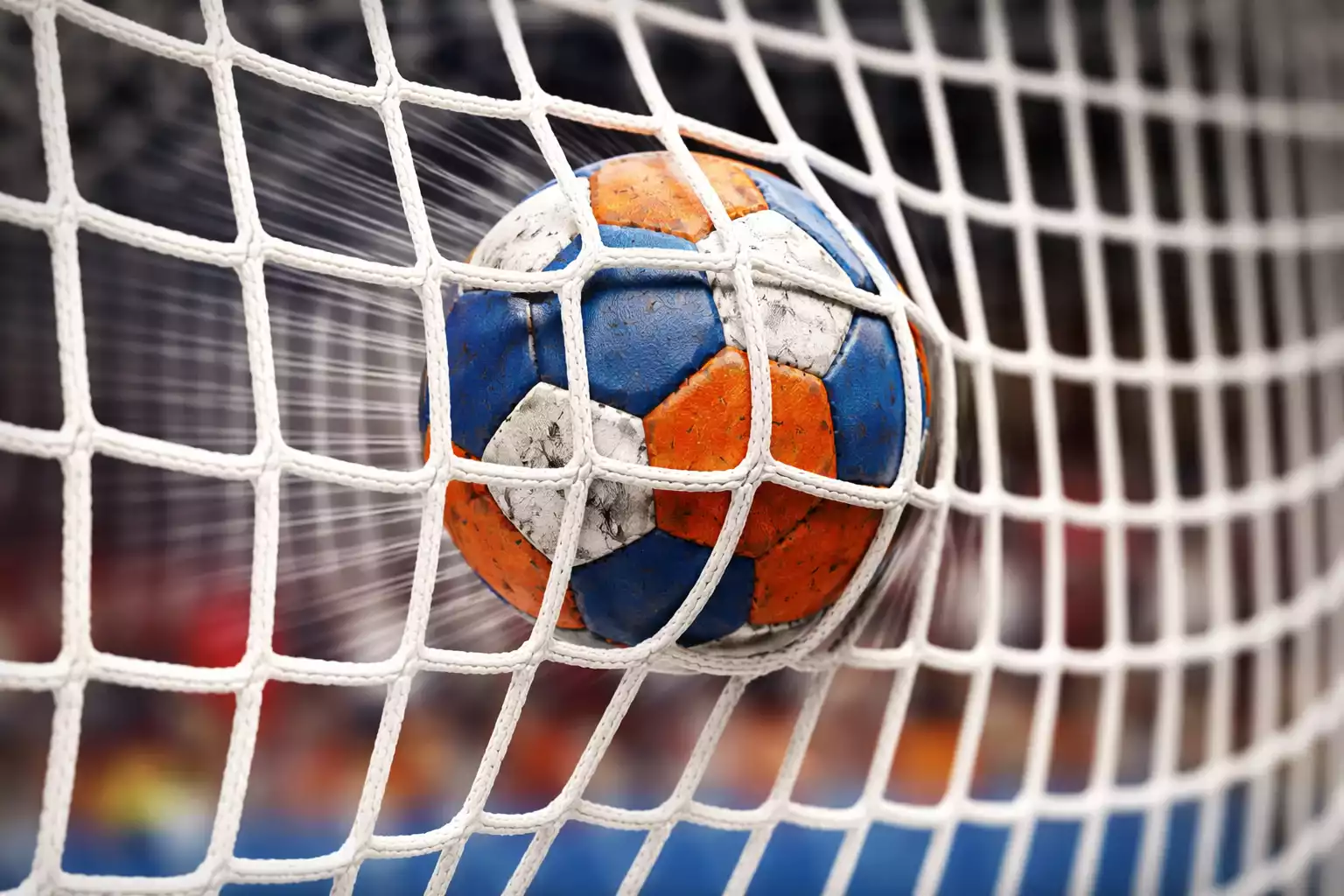 Ballon de handball franchissant la ligne de but dans un filet lors d'un match professionnel